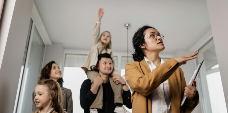 A real estate agent shows a happy family their potential new home in a bright, modern setting.